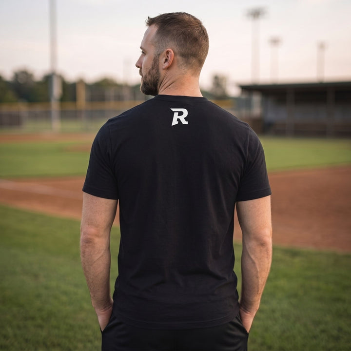 A man viewed from behind wearing a RIPPASHOT black short-sleeve t-shirt with a white stylized &