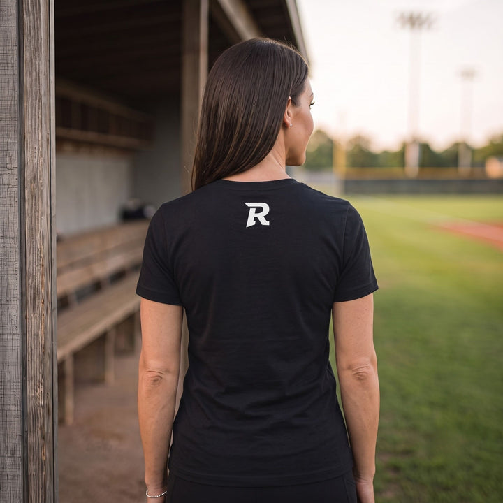 A woman viewed from behind wearing a  RIPPASHOT black short-sleeve athletic T-shirt with a white stylized &