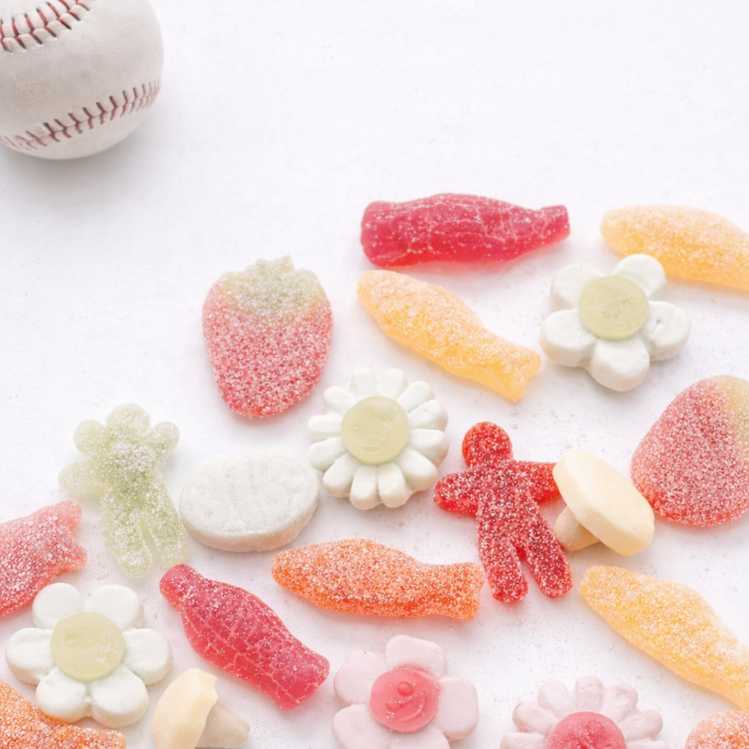 Assorted colorful gummy candies on a white surface with a baseball in the corner.